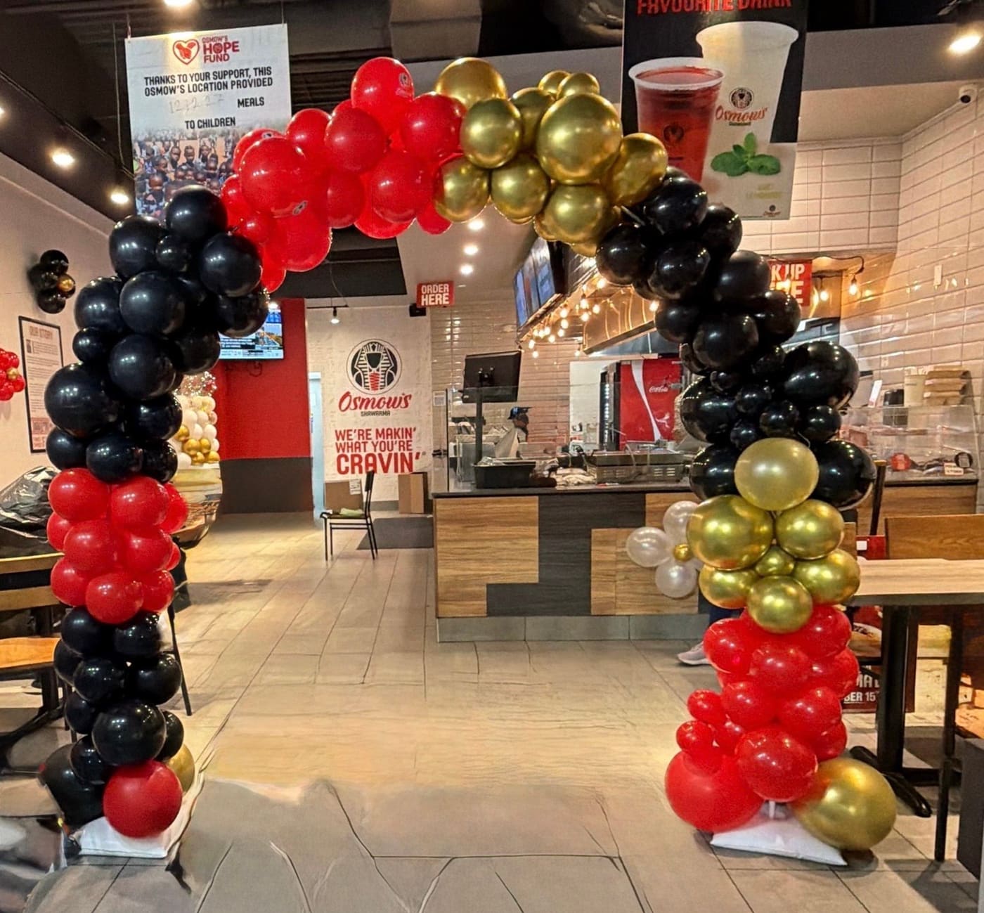Red, black and gold balloon arch by Charisma Party Decor
